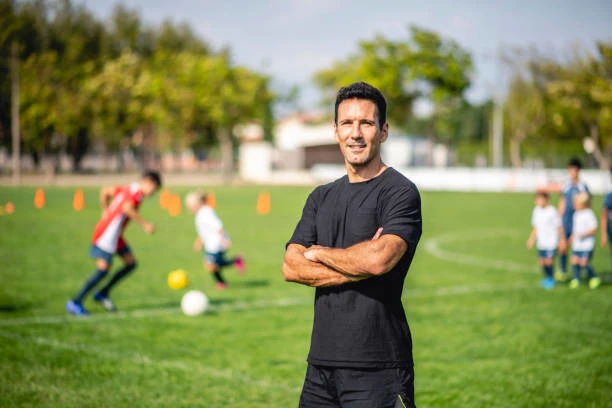 trainer looking proud into the camera at a football field